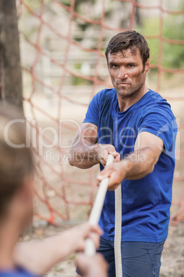 Man and woman playing tug of war during obstacle course