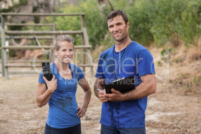 Trainer and woman standing together during obstacle course