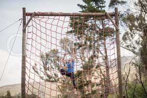 Fit woman climbing a net during obstacle course