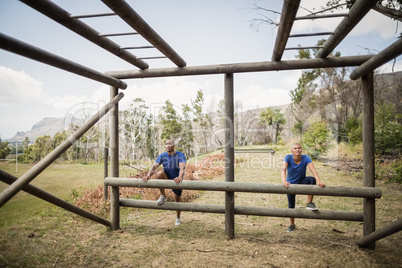 Fit man and woman climbing monkey bars during obstacle course