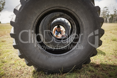 Man crawling through the tire during obstacle course
