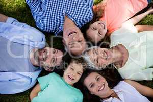 Multi generation family lying in park in a circle
