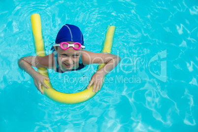 Little girl swimming with pool noodle
