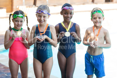 Little swimmers showing medals at poolside