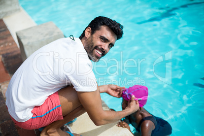 Male instructor assisting girl at poolside