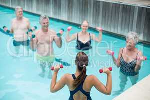 Trainer assisting senior swimmer in weightlifting