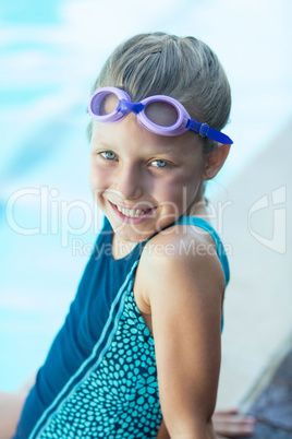 Smiling little girl sitting at poolside