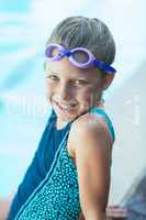 Smiling little girl sitting at poolside