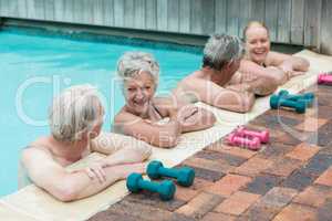 Cheerful swimmers leaning on poolside