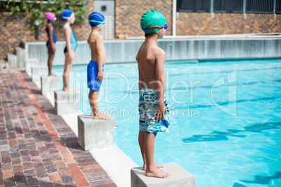 Swimmers standing on starting blocks at poolside