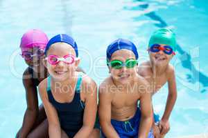 Little swimmers sitting at poolside