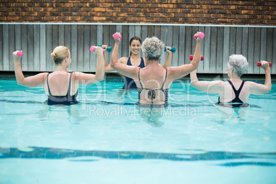 Senior swimmers lifting dumbbells in swimming pool