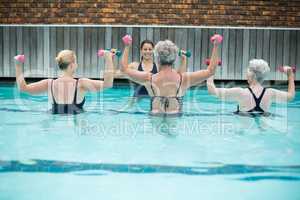 Senior swimmers lifting dumbbells in swimming pool