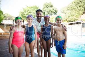 Little swimmers with trainer standing at poolside