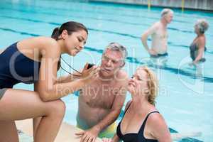 Female trainer showing time to senior swimmers at poolside