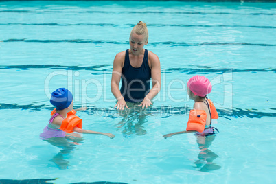 Female instructor assisting children in swimming pool
