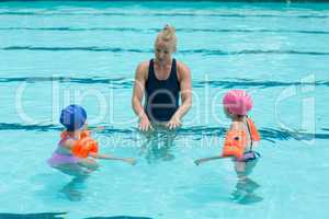 Female instructor assisting children in swimming pool