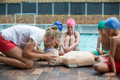 Female lifeguard demonstrating children during rescue training