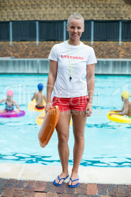 Female lifeguard holding rescue can at poolside