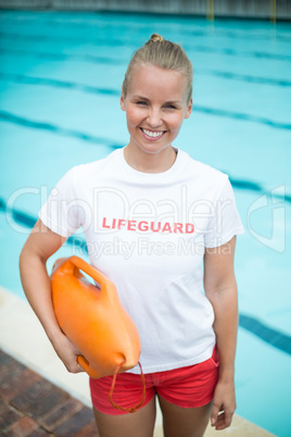 Portrait of lifeguard holding rescue can at poolside