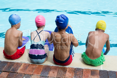 Girls and boys sitting at poolside