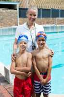 Swimming instructor with boys at poolside
