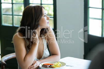 Thoughtful woman sitting at restaurant table