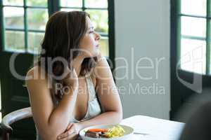 Thoughtful woman sitting at restaurant table