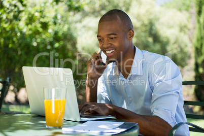 Businessman using laptop and smart phone at restaurant