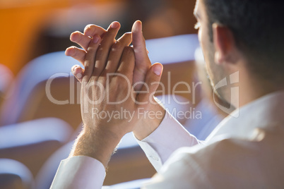 Business executive clapping while listening to speech