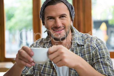 Portrait of smiling man holding coffee cup in cafeteria