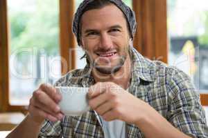 Portrait of smiling man holding coffee cup in cafeteria