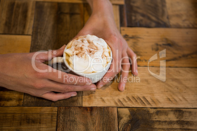 Man hands holding coffee cup at table in cafeteria