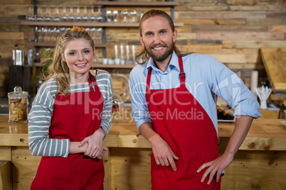 Smiling male and female baristas at counter in coffee shop