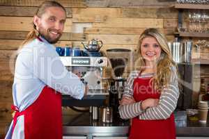 Baristas standing by coffee machine at cafeteria
