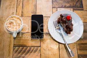 Smart phone with pastry and coffee cup on table