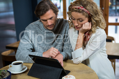 Couple using digital tablet at table in coffee shop