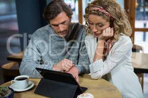 Couple using digital tablet at table in coffee shop