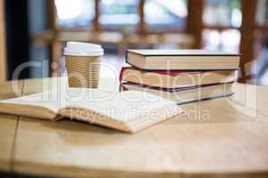 Books and disposable coffee cup on table in cafe