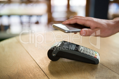 Customer paying through smart phone in coffee shop