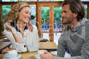 Smiling couple talking at table in cafeteria