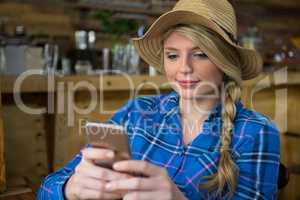 Woman wearing hat while using mobile phone in coffee shop