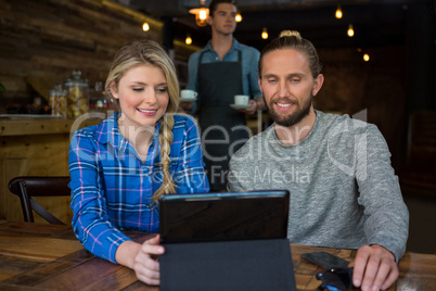 Couple using tablet computer at table in coffee shop