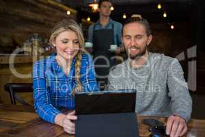 Couple using tablet computer at table in coffee shop
