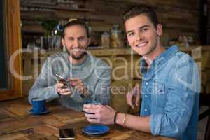 Portrait of smiling men sitting at table in coffee shop