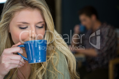 Young woman drinking coffee in cafeteria