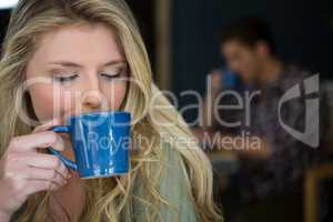 Young woman drinking coffee in cafeteria