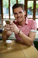 Handsome young man using mobile phone in cafe