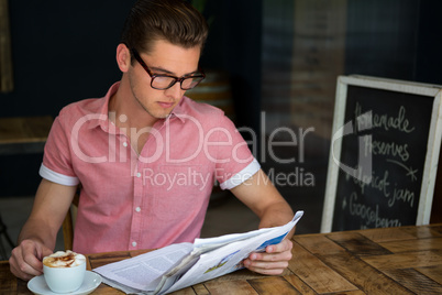 Man reading newspaper while having coffee in cafe