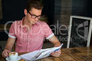 Man reading newspaper while having coffee in cafe